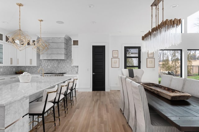 dining area with light wood-type flooring, an inviting chandelier, baseboards, and recessed lighting