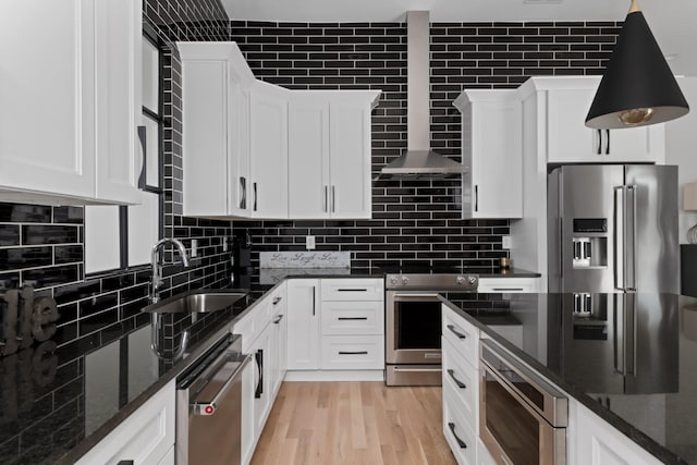 kitchen with stainless steel appliances, dark stone countertops, a sink, and white cabinets