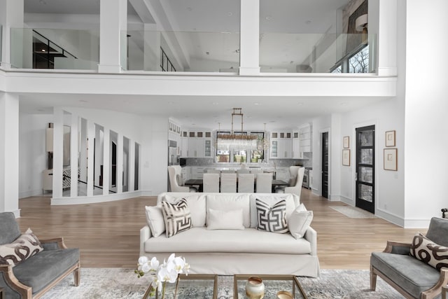 living room with baseboards, light wood-style flooring, and a towering ceiling