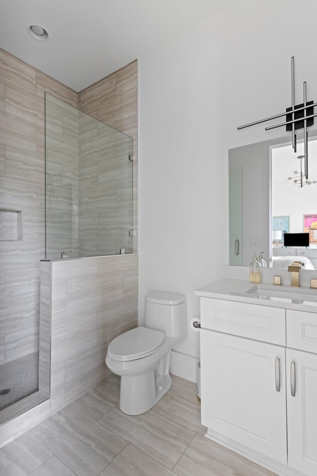 bathroom featuring tiled shower, vanity, toilet, and ensuite bathroom