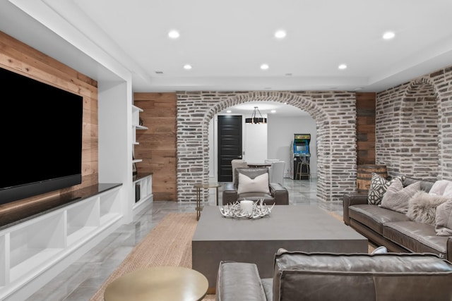 living area featuring brick wall, wooden walls, arched walkways, and recessed lighting