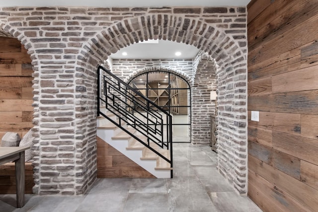 wine area featuring wood walls and arched walkways