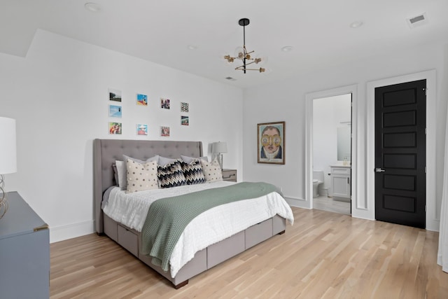 bedroom featuring a notable chandelier, visible vents, ensuite bathroom, light wood-type flooring, and baseboards