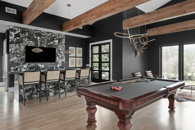 recreation room with a wealth of natural light, light wood-style flooring, visible vents, and beam ceiling