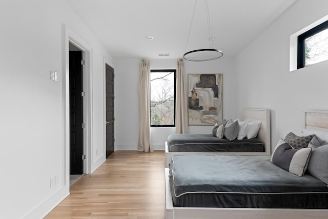 bedroom with light wood finished floors, visible vents, multiple windows, and baseboards