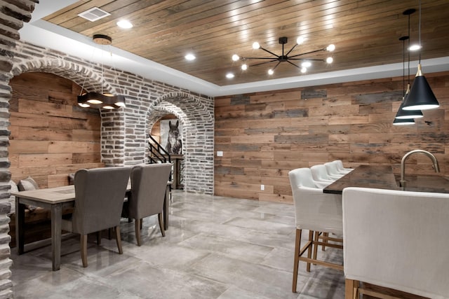 wine room featuring arched walkways, recessed lighting, wood walls, wood ceiling, and a tray ceiling