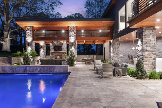 outdoor pool with an outdoor stone fireplace and a patio area