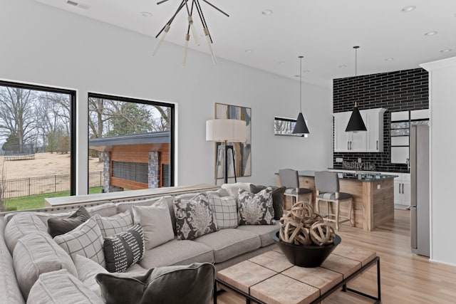 living room featuring a chandelier, light wood-type flooring, visible vents, and recessed lighting