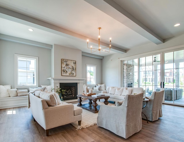 living area featuring a fireplace with flush hearth, beam ceiling, and wood finished floors