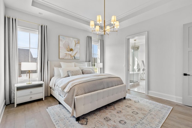 bedroom featuring a chandelier, a tray ceiling, wood finished floors, and baseboards