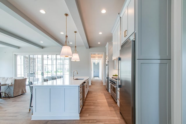 kitchen with premium appliances, beam ceiling, light countertops, open floor plan, and light wood-type flooring