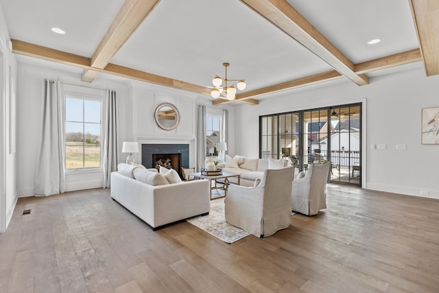 living room featuring light wood finished floors, baseboards, beamed ceiling, a chandelier, and a high end fireplace