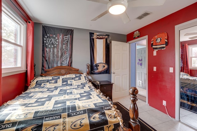 bedroom featuring light tile patterned floors, multiple windows, visible vents, and a ceiling fan