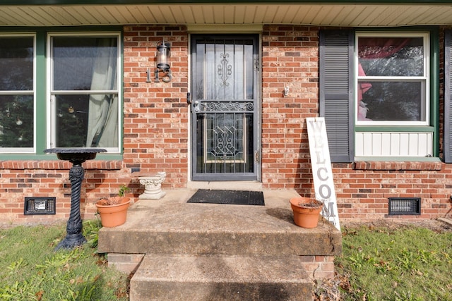 property entrance with brick siding and crawl space