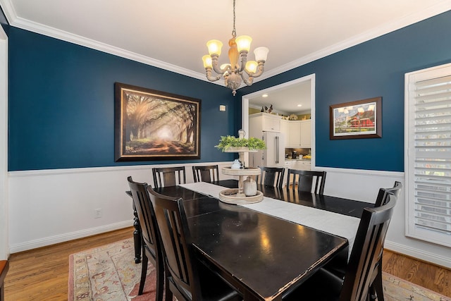 dining room with a notable chandelier, baseboards, light wood-style flooring, and crown molding