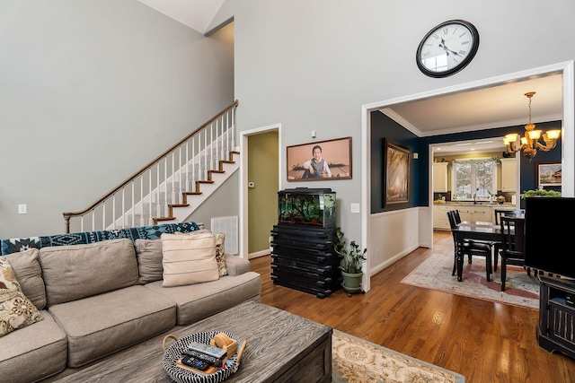 living room featuring crown molding, visible vents, stairway, an inviting chandelier, and wood finished floors