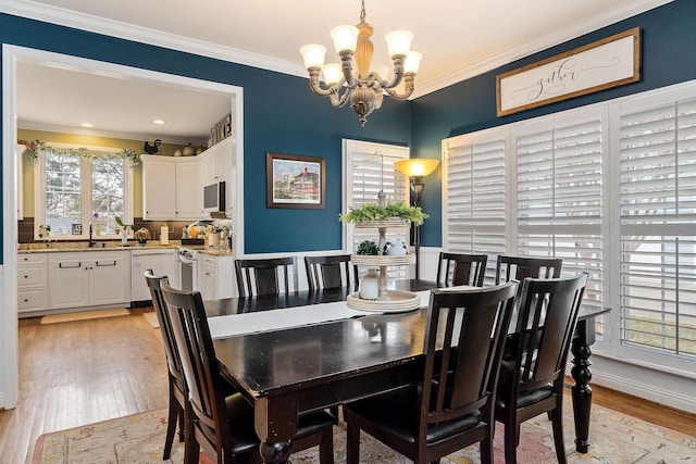 dining area with ornamental molding, light wood-style floors, baseboards, and an inviting chandelier