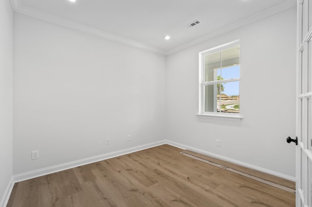 empty room featuring light wood finished floors, ornamental molding, visible vents, and baseboards