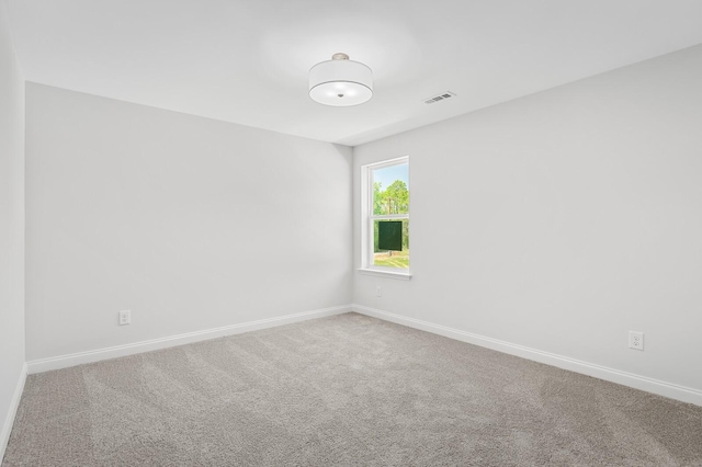 carpeted spare room with visible vents and baseboards