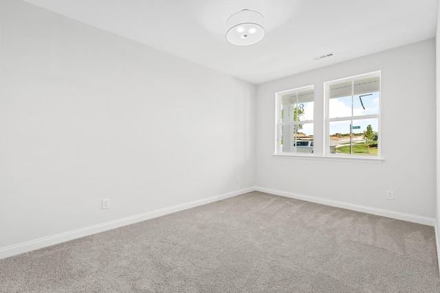 empty room featuring carpet, visible vents, and baseboards