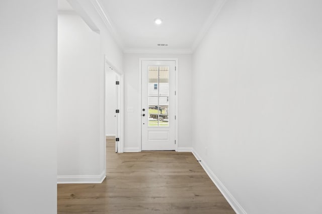 doorway to outside with baseboards, light wood-style floors, visible vents, and crown molding