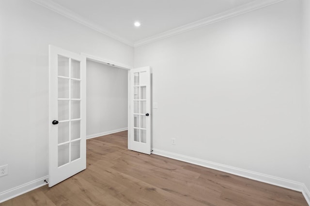 spare room with baseboards, french doors, light wood finished floors, and crown molding