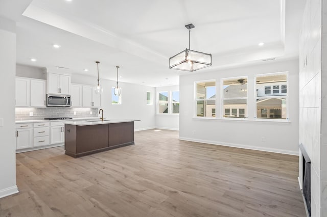 kitchen featuring pendant lighting, stainless steel microwave, white cabinets, and open floor plan