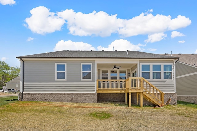 back of property with a ceiling fan, a yard, and stairs