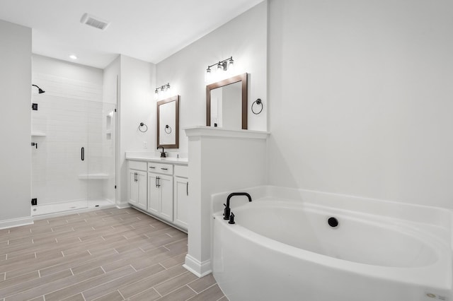 bathroom featuring wood finish floors, visible vents, a stall shower, vanity, and a bath