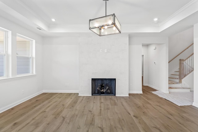 unfurnished living room with a raised ceiling, ornamental molding, stairway, and wood finished floors