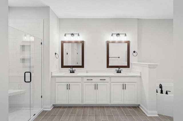 bathroom with double vanity, a stall shower, a sink, and wood tiled floor