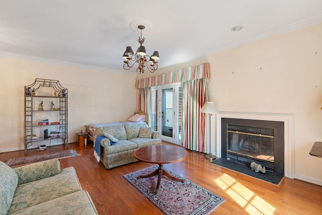 living area with a fireplace with flush hearth, baseboards, crown molding, and wood finished floors