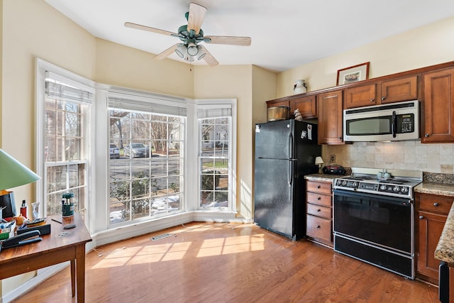 kitchen featuring electric range oven, stainless steel microwave, plenty of natural light, and freestanding refrigerator