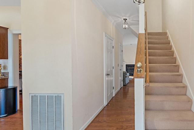 stairs with ornamental molding, visible vents, baseboards, and wood finished floors