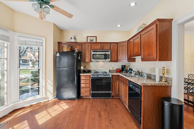 kitchen featuring backsplash, dark wood-type flooring, a sink, light stone countertops, and black appliances