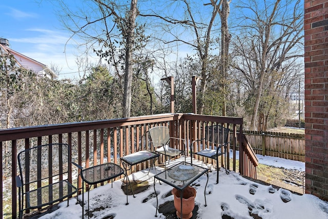 snow covered deck featuring a playground and fence