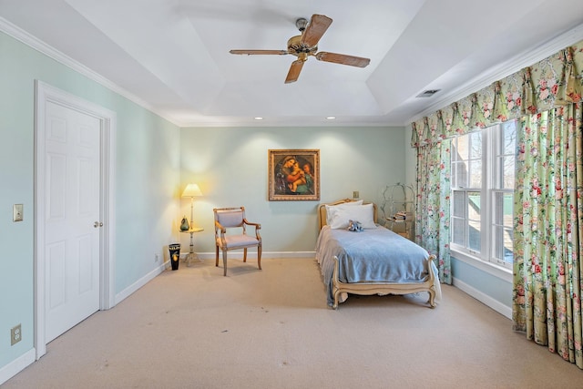 carpeted bedroom with crown molding, a tray ceiling, and baseboards