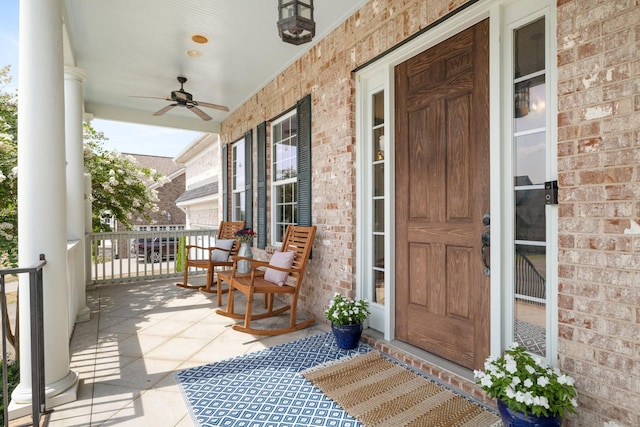 property entrance featuring a porch, brick siding, and ceiling fan