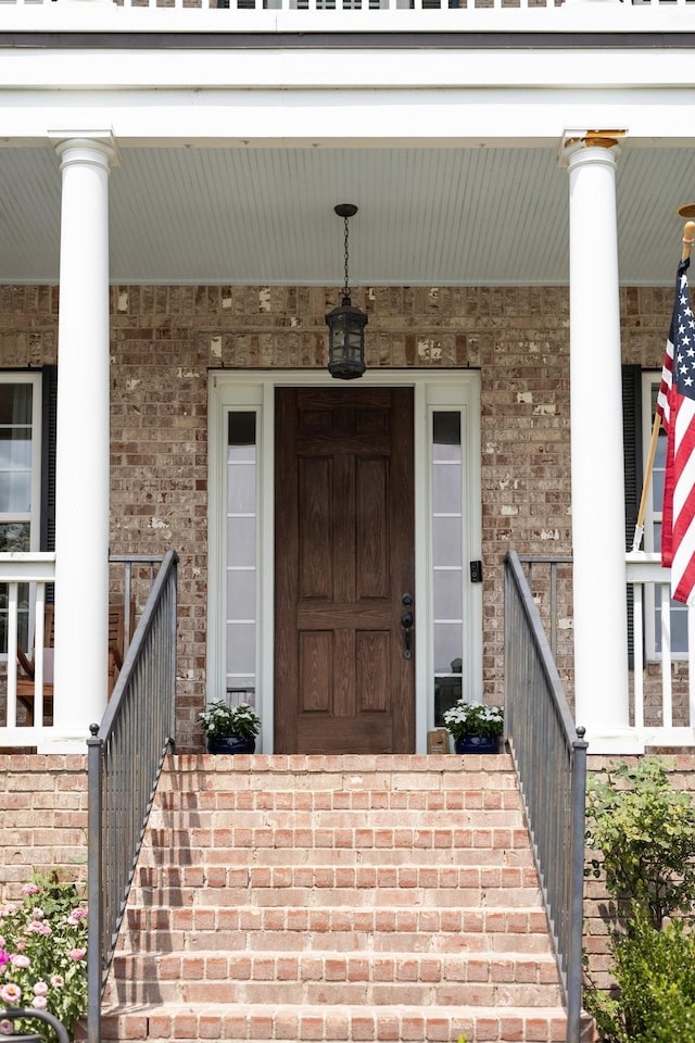 entrance to property featuring covered porch and brick siding