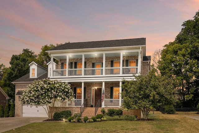 view of front facade featuring a porch, concrete driveway, a lawn, and a balcony