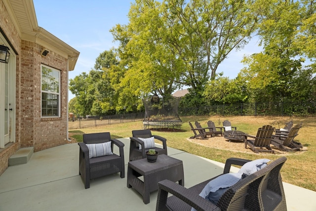 view of patio / terrace with an outdoor fire pit, a trampoline, and a fenced backyard