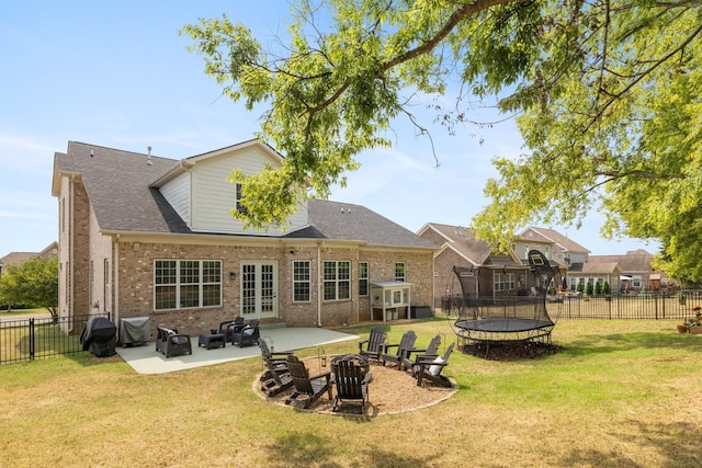 back of property featuring a trampoline, brick siding, a lawn, a patio area, and a fenced backyard