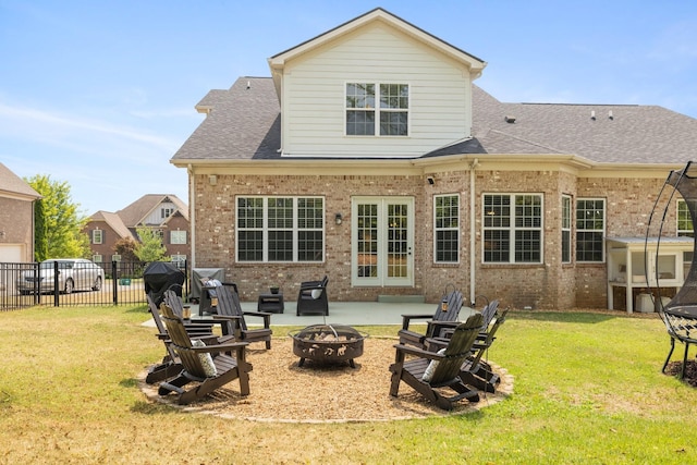 rear view of house with an outdoor fire pit, a lawn, and brick siding