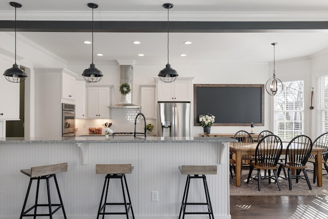 kitchen with white cabinetry, light stone countertops, wall chimney exhaust hood, and appliances with stainless steel finishes