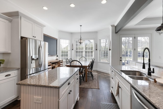 kitchen featuring a kitchen island, a sink, white cabinetry, appliances with stainless steel finishes, and pendant lighting