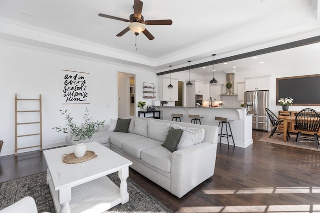 living room featuring dark wood-style flooring, recessed lighting, a raised ceiling, ornamental molding, and a ceiling fan