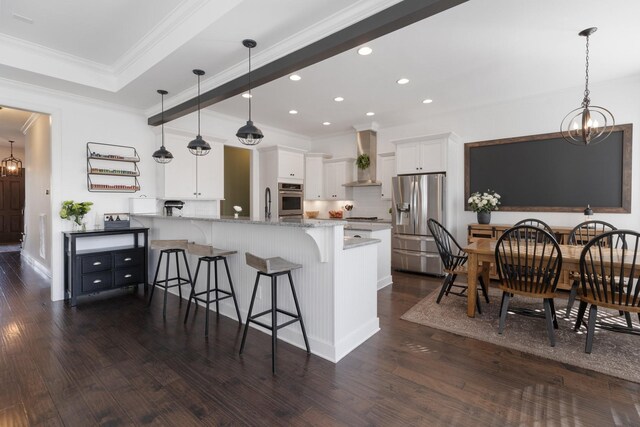 kitchen featuring white cabinets, appliances with stainless steel finishes, a peninsula, light stone countertops, and a chandelier