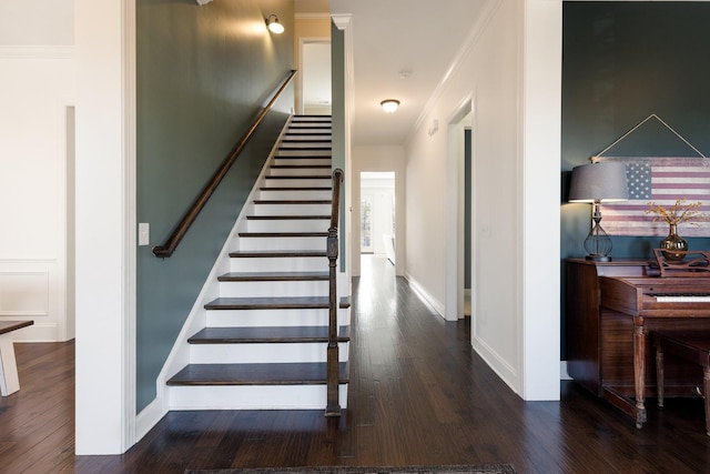 staircase with ornamental molding, wood finished floors, and baseboards