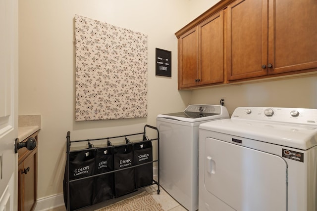 clothes washing area with baseboards, cabinet space, washing machine and clothes dryer, and light tile patterned floors