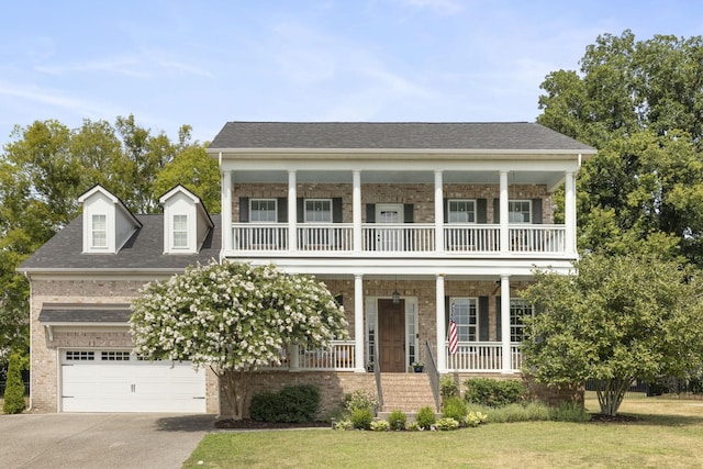 view of front of property featuring brick siding, concrete driveway, roof with shingles, a porch, and a front yard